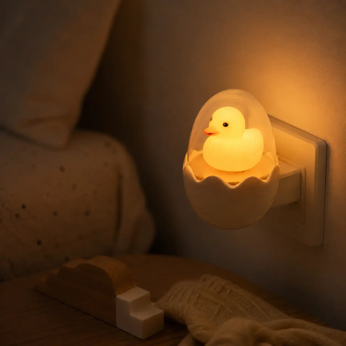 Veilleuse prise murale canard dans son œuf allumée diffusant une lumière douce dans une chambre d'enfant