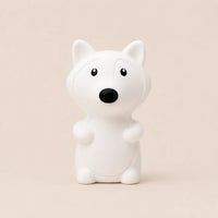 Veilleuse en silicone en forme de petit renard blanc, sur un fond beige neutre.