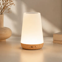 Veilleuse scandinave avec base en bois allumée diffusant une lumière chaude et tamisée dans un intérieur minimaliste.