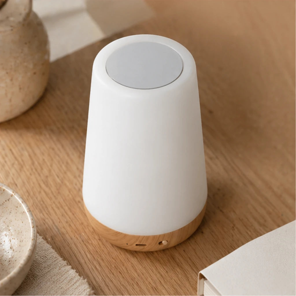 Lampe veilleuse scandinave éteinte avec socle effet bois et partie supérieure blanche posée sur un meuble en bois clair.