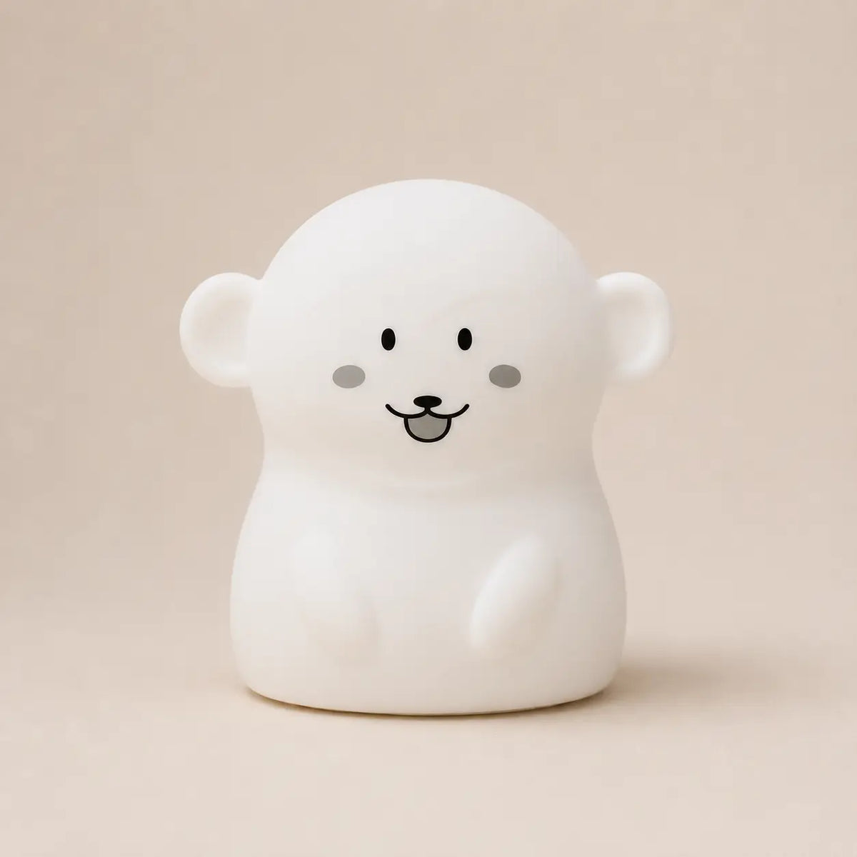 Veilleuse en silicone en forme de petit singe blanc, sur un fond beige neutre.