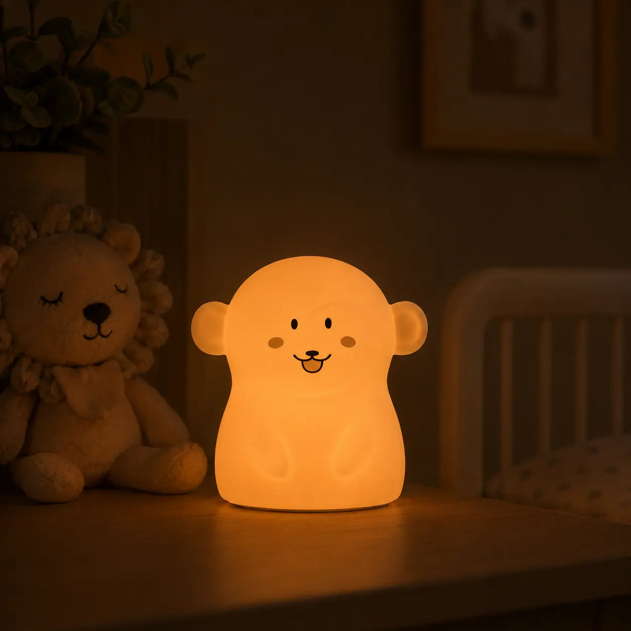 Veilleuse en forme de petit singe allumée posée sur une table de chevet dans une ambiance chaleureuse.