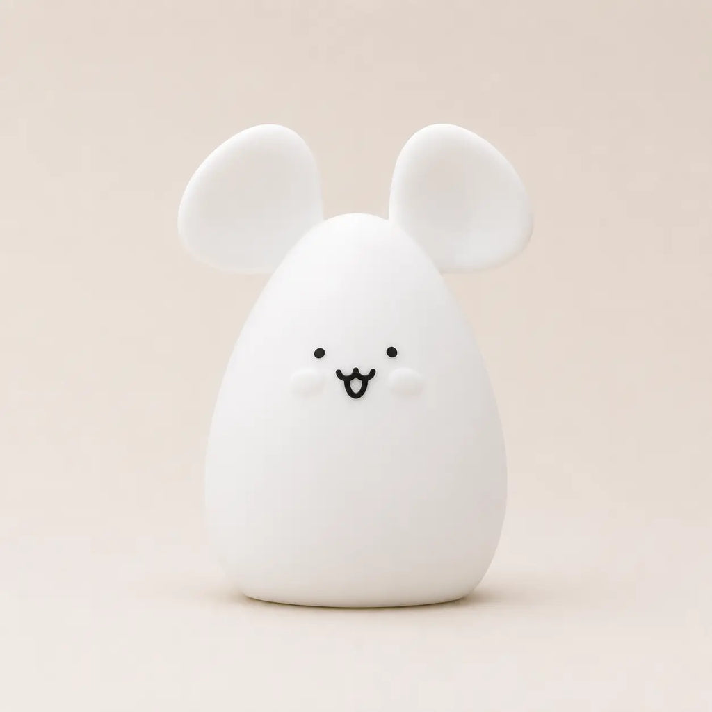 Veilleuse en silicone en forme de petite souris blanche, sur un fond beige neutre.