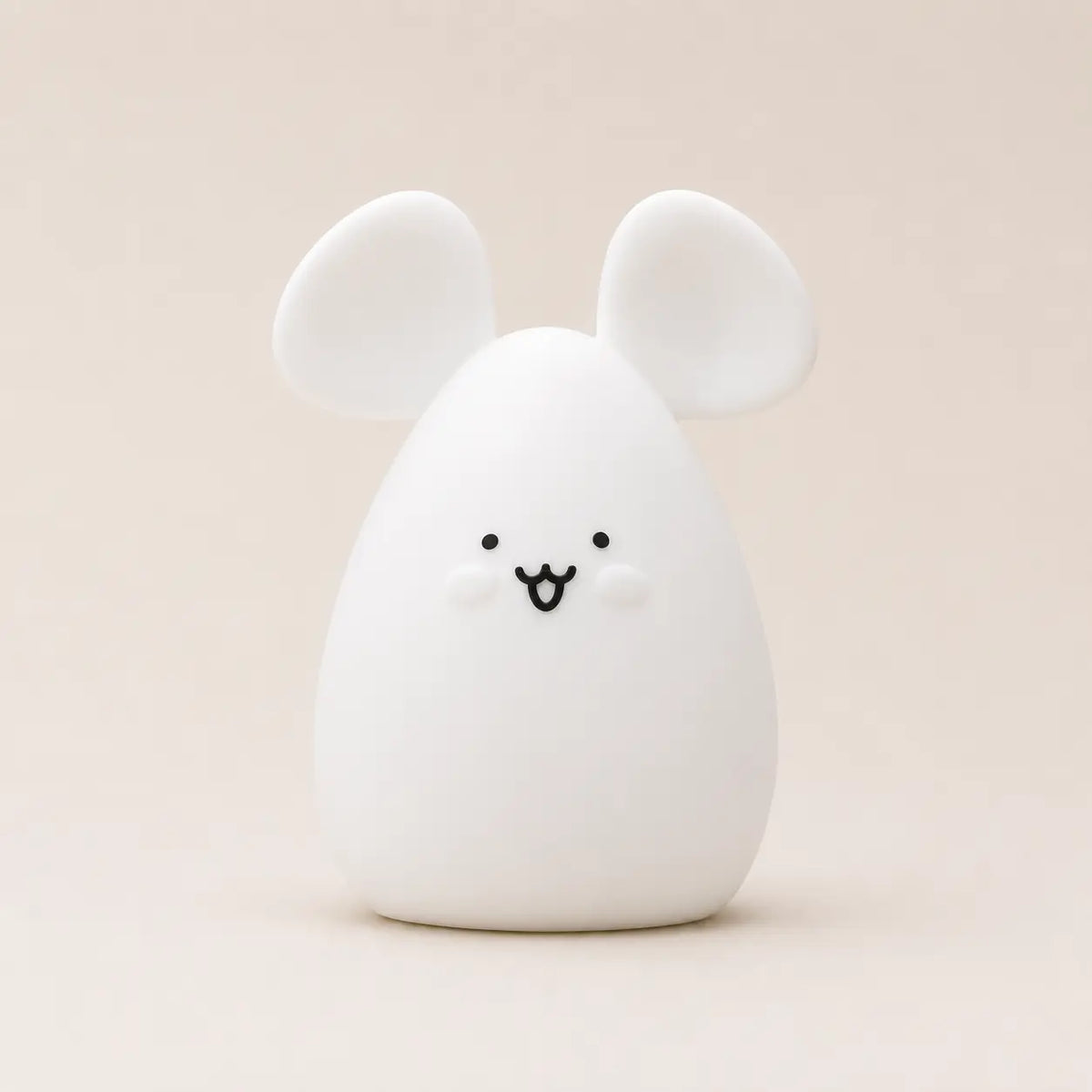 Veilleuse en silicone en forme de petite souris blanche, sur un fond beige neutre.