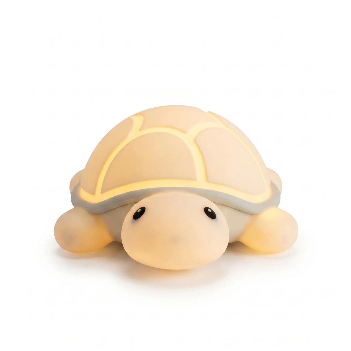 Veilleuse nomade en silicone souple en forme de petite tortue mignonne, allumée et diffusant une douce lueur chaude et tamisée à travers sa carapace, présentée de face sur fond blanc.
